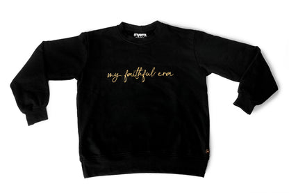 A black crewneck sweatshirt with 'my faithful era' embroidered in gold cursive across the chest, displayed flat against a white background.